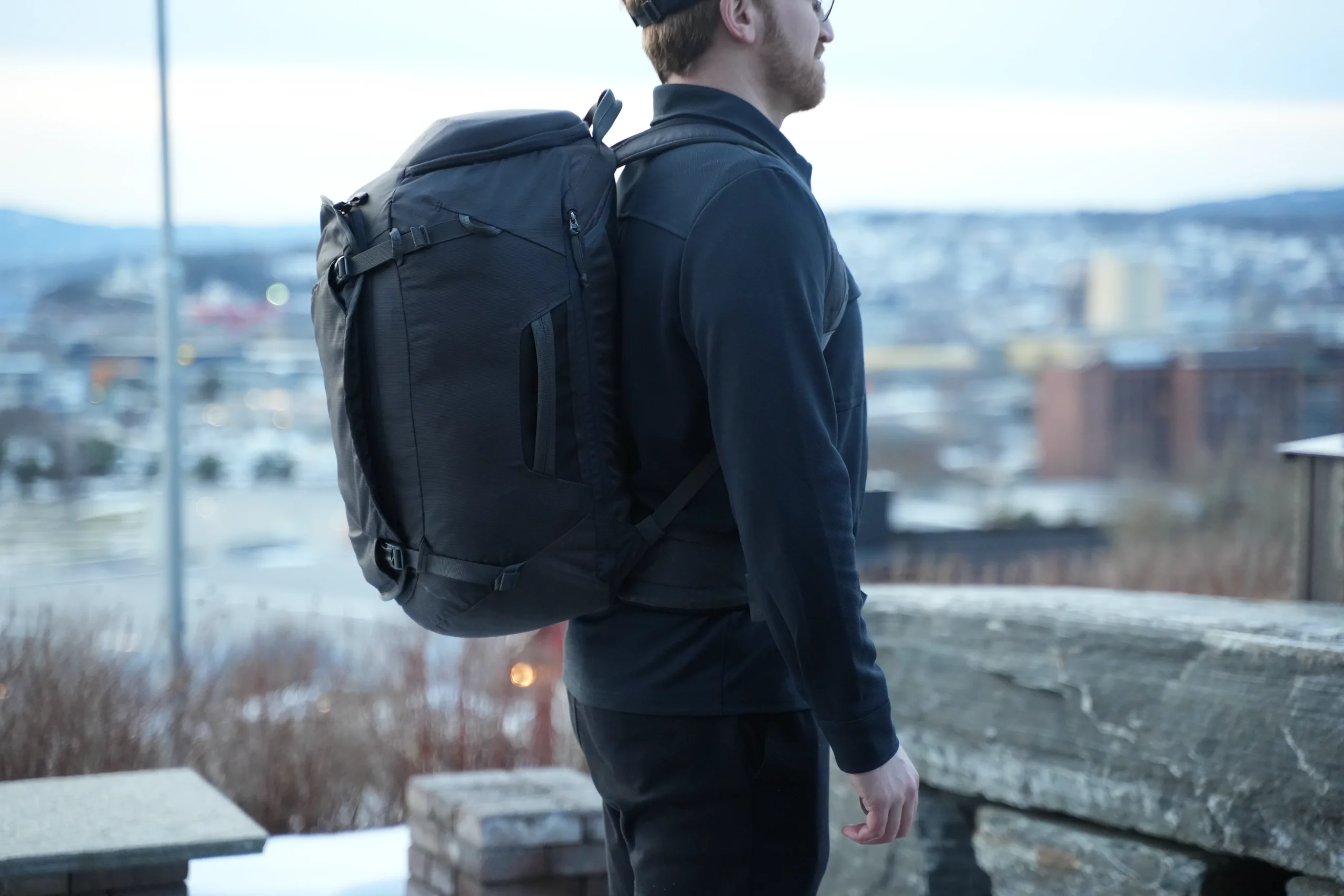 Thule Landmark 40 worn from rear quarter angle showing shape and green tint with city view