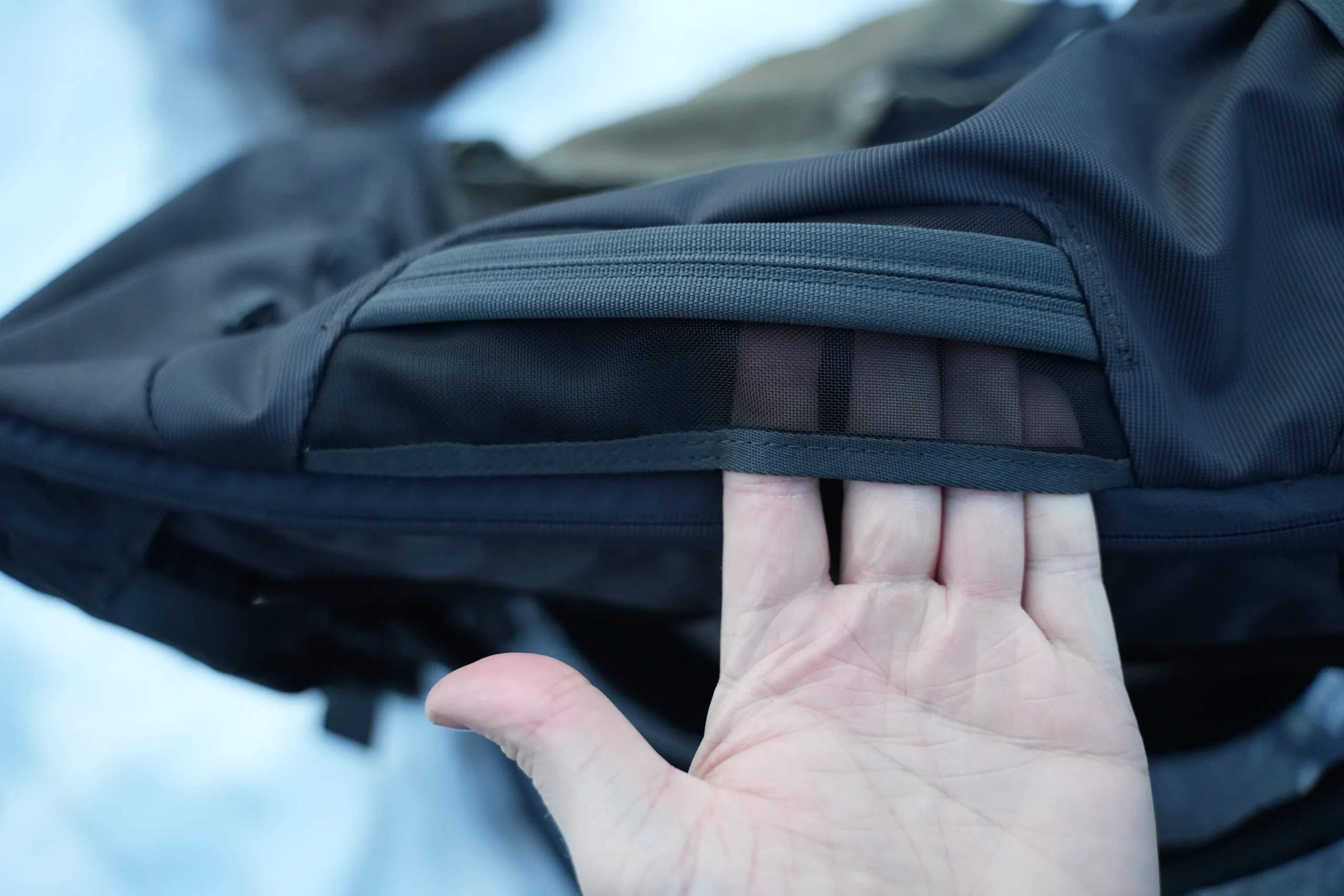 Thule Landmark 40 hidden CashStash pocket being revealed by hand