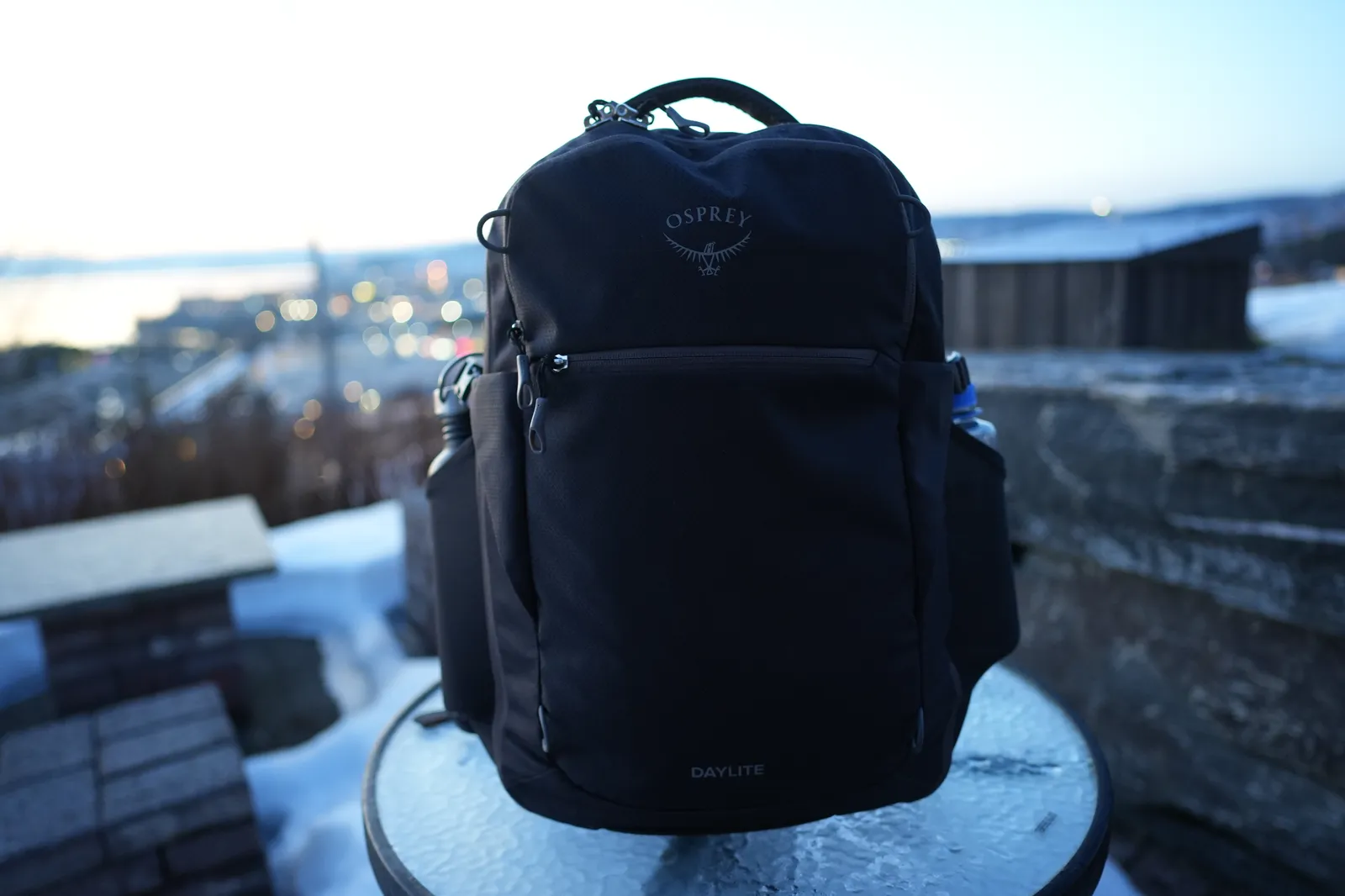 Osprey Daylite 35 backpack front view with Osprey logo and DAYLITE branding, photographed outdoors with city lights in the background at dusk