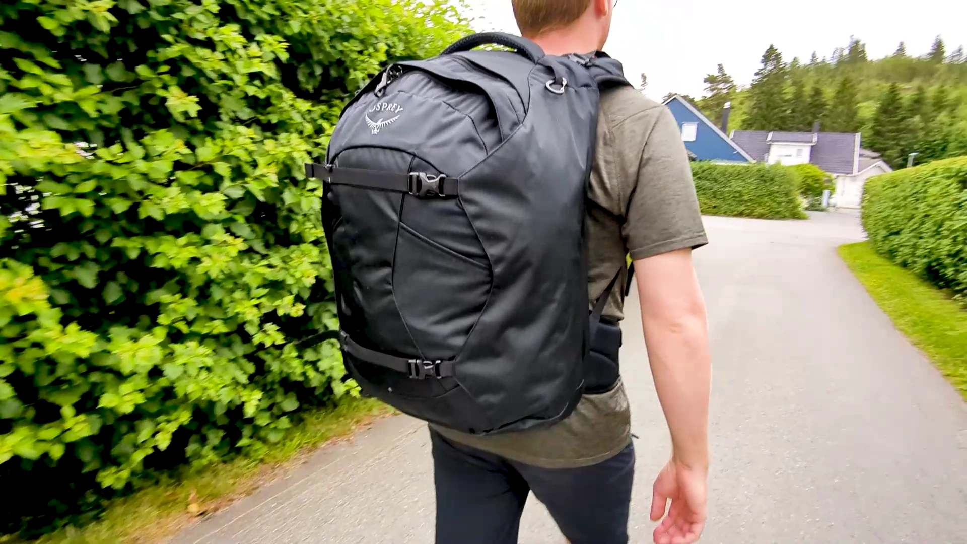Person walking on a suburban path from behind wearing the Osprey Farpoint 40