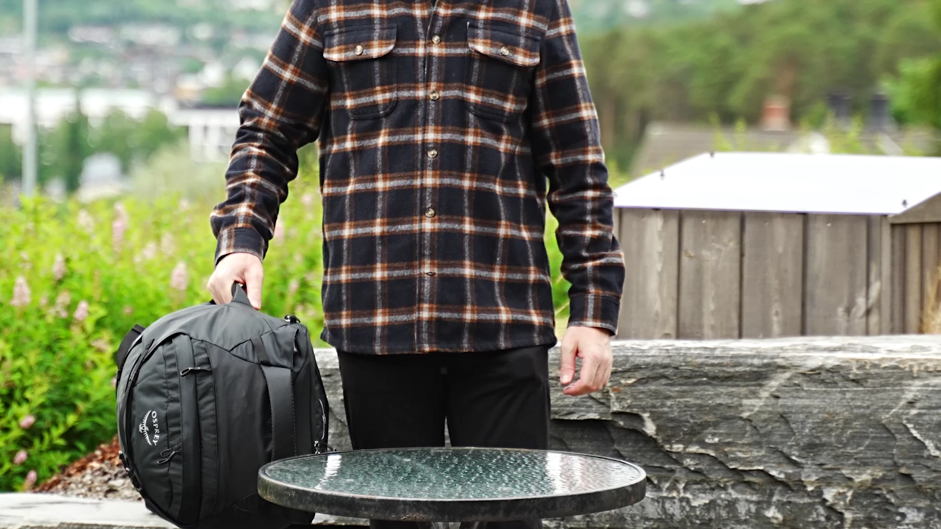 Person holding the Osprey Farpoint 40 in compact stowed mode by the top handle