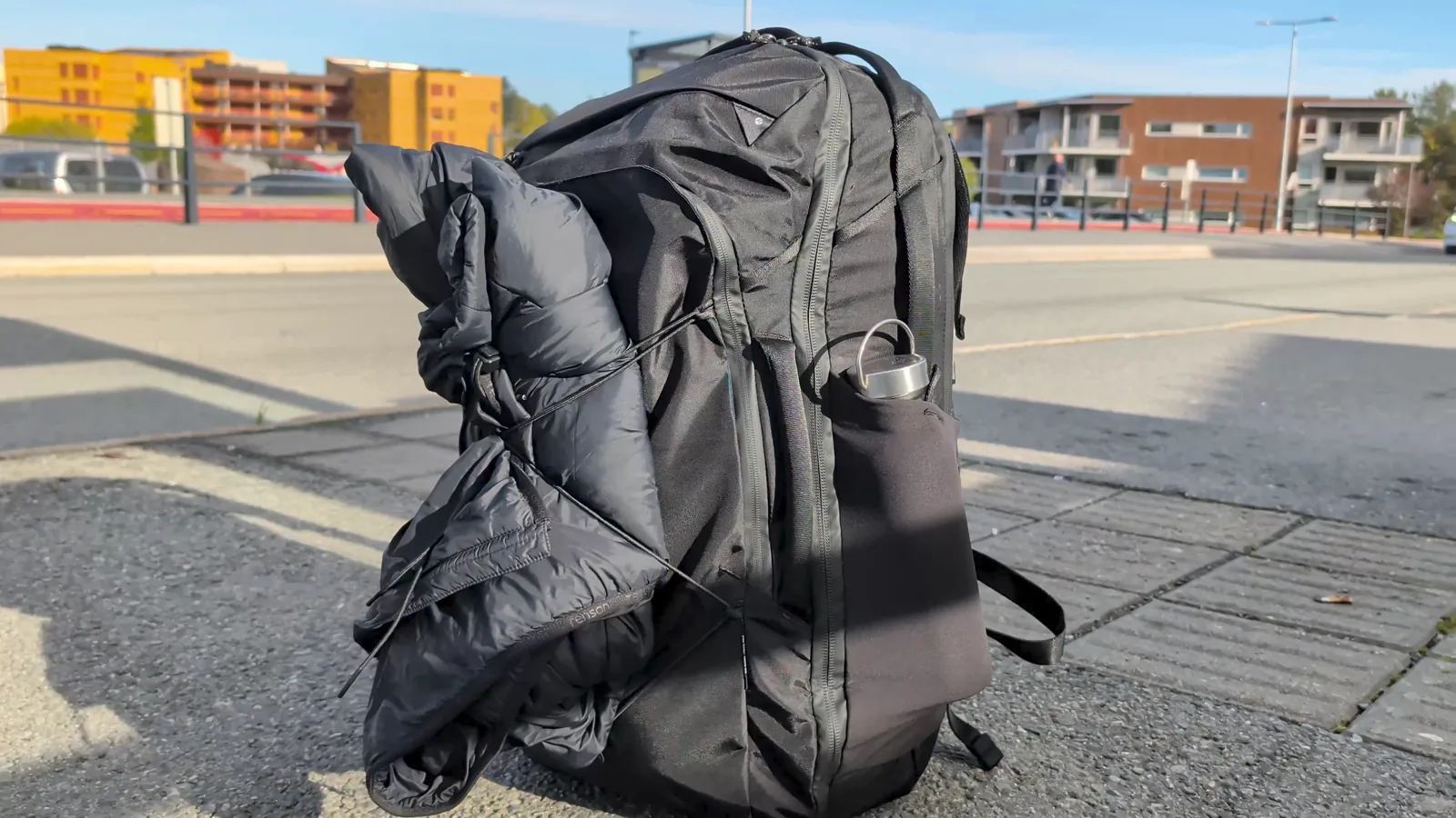 A jacket held by the elastic cord on the front of the Matador Global Travel Pack 35