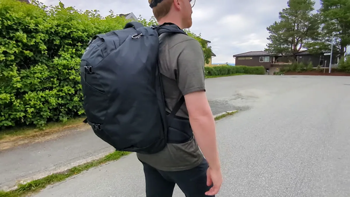 HMMüller walking beside a hedge with a loaded Osprey Farpoint 40 on his back.